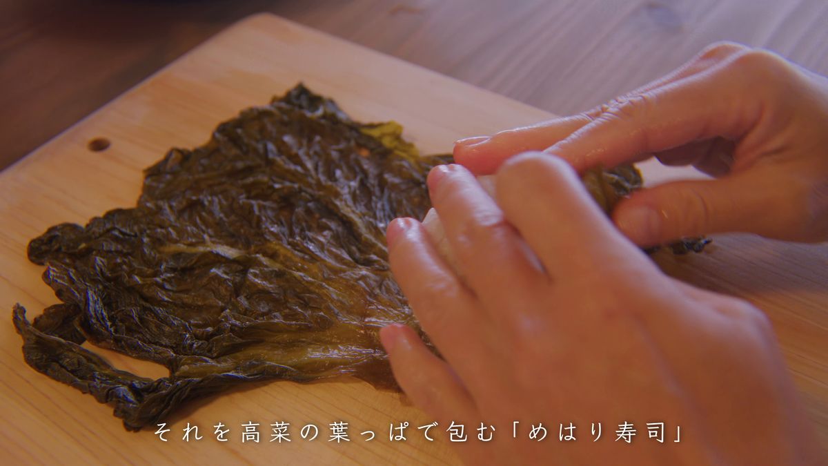 広げた高菜の葉でおにぎりを包む
