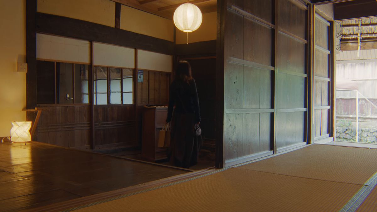 提灯の灯る板の間に立つ後ろ姿