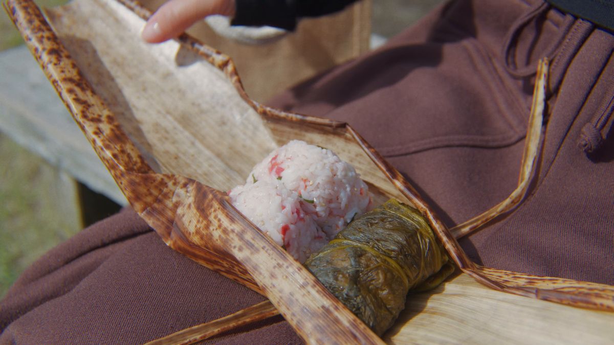 膝の上で竹の皮の包みを開く手元