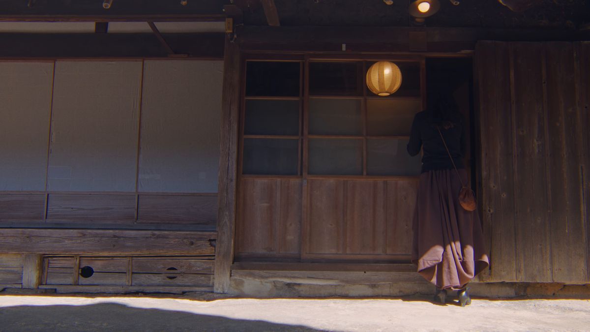 古民家の玄関の戸を開ける後ろ姿