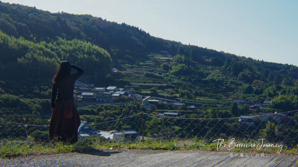 石垣の段々畑と集落を見下ろす後ろ姿