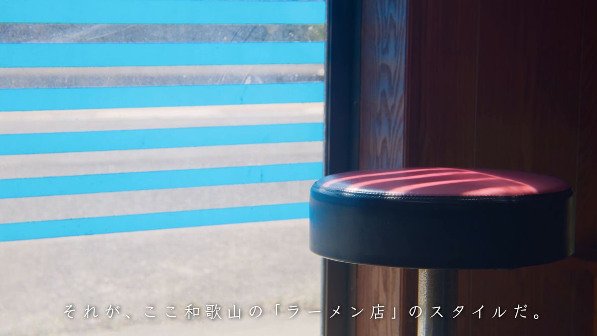 青い縞の窓辺に置かれた赤い丸椅子