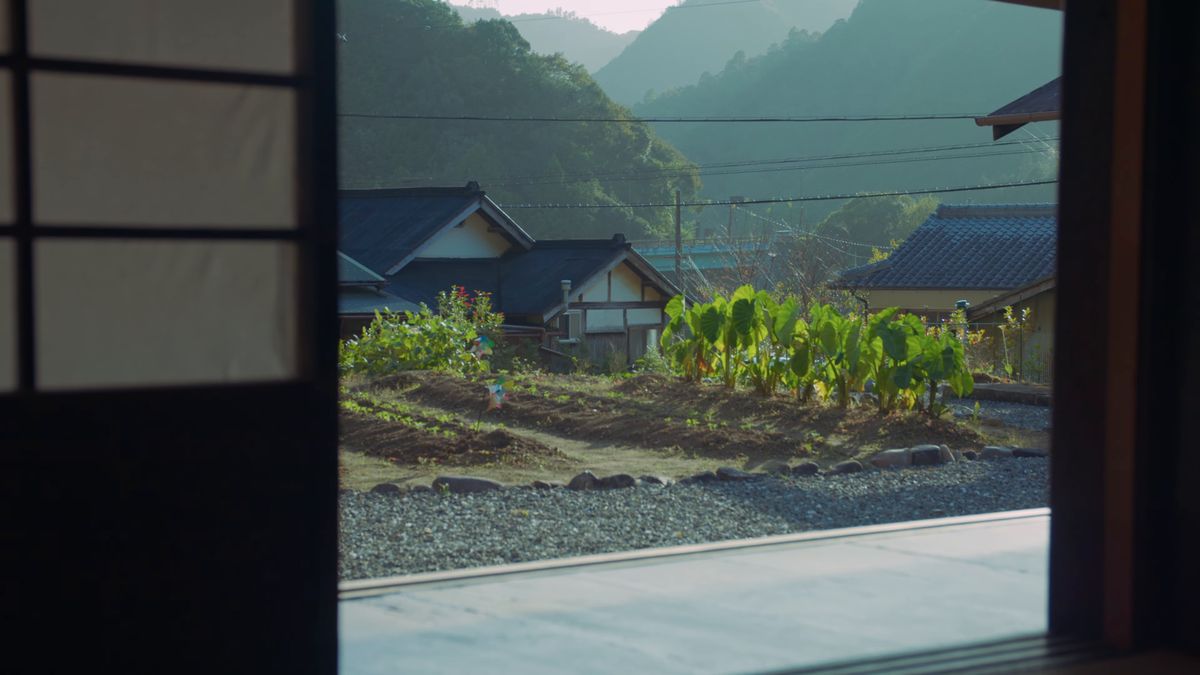 戸口の向こうに広がる畑と家々と山