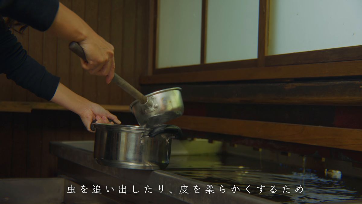 水槽の脇で鍋に水を汲む手元