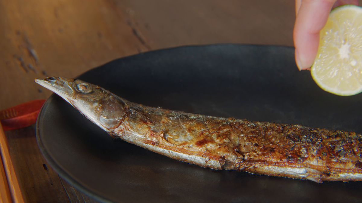 焼きサンマにすだちを絞る