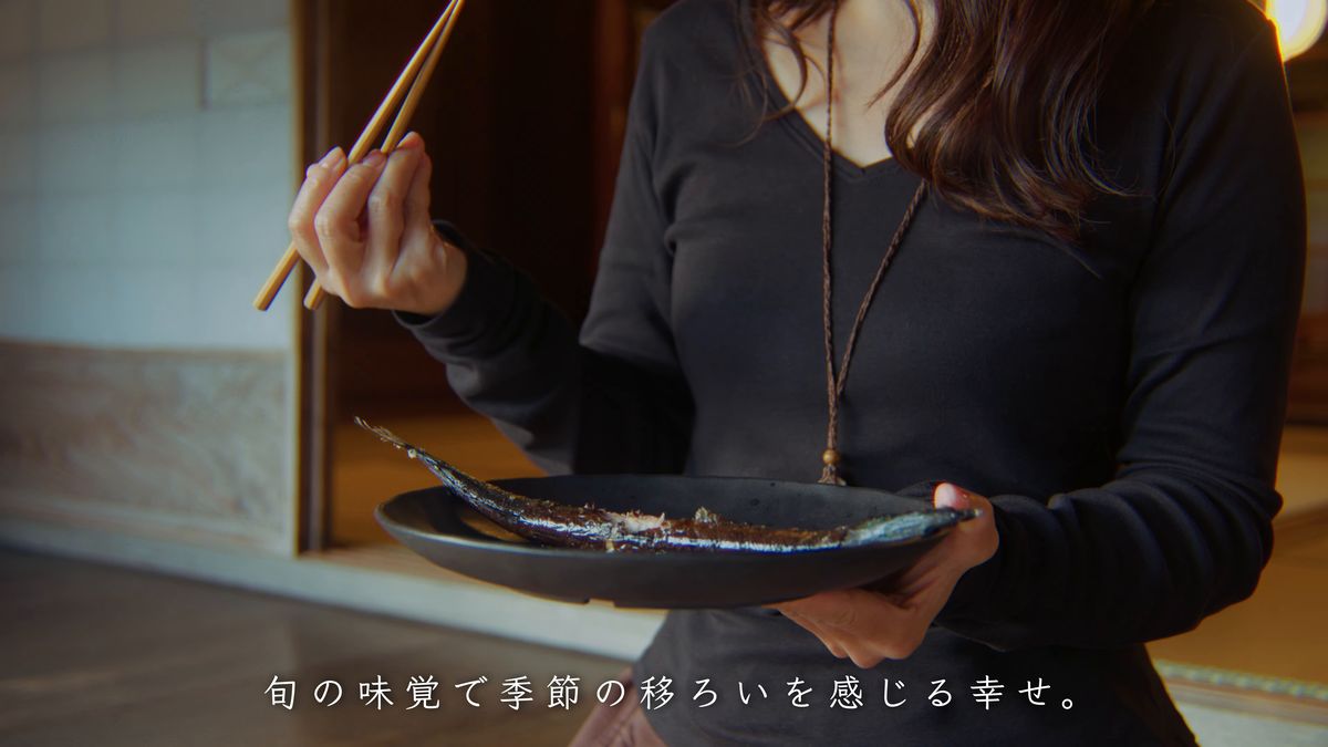 皿を手にサンマを食べる