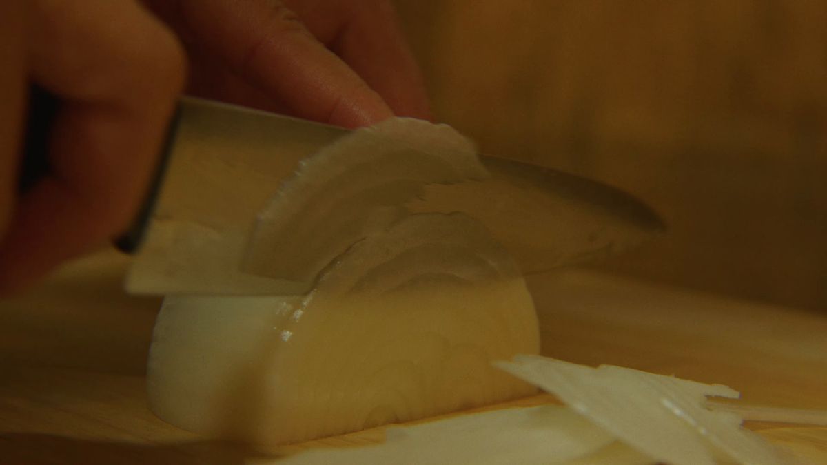 玉ねぎを薄切りにする手元