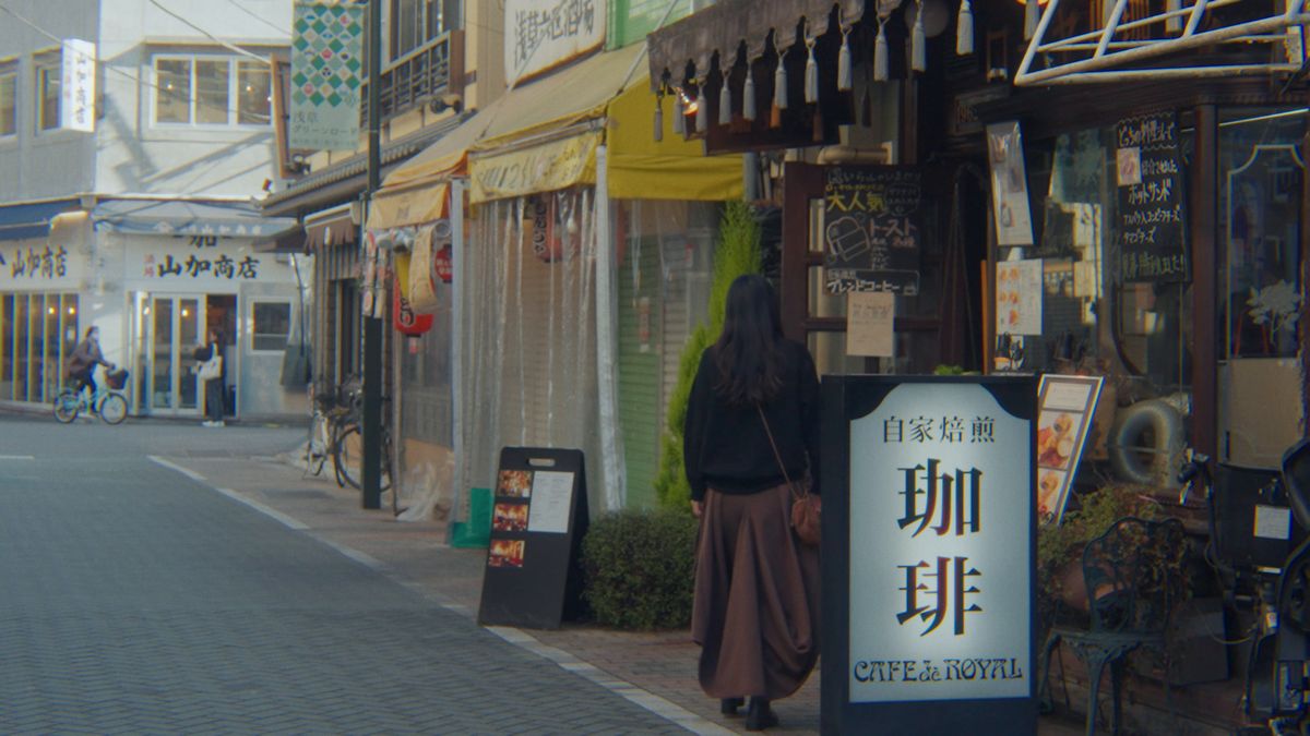 「自家焙煎 珈琲」の看板の前を通る後ろ姿