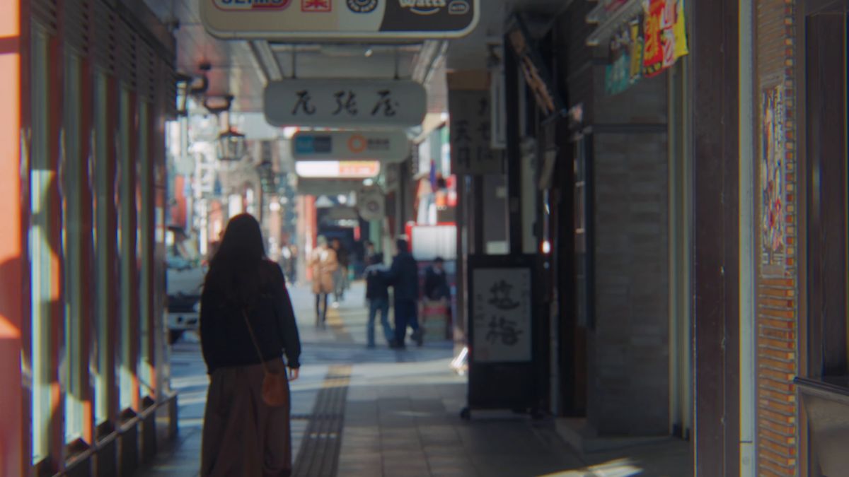 吊り看板の下がる歩道を歩く後ろ姿
