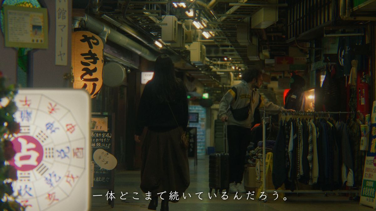 占いの看板と古着のラックが並ぶ通路