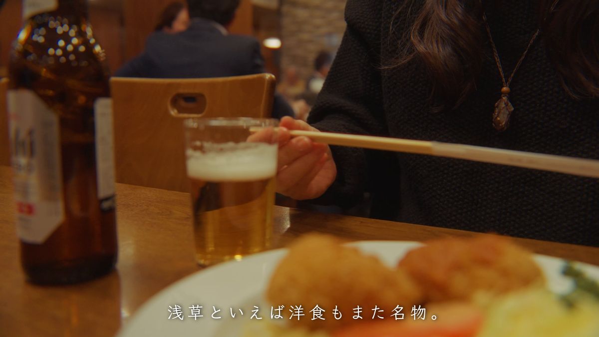 グラスを手に、かにコロッケの皿を前にする