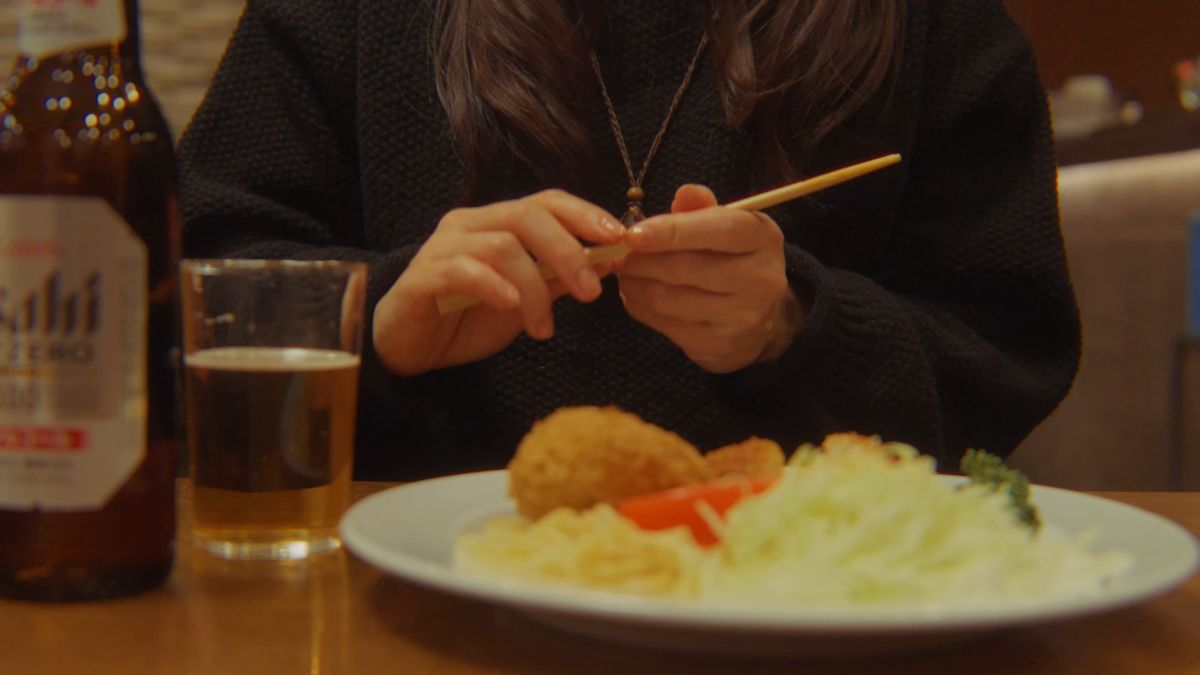 かにコロッケの皿を前に箸を手にする