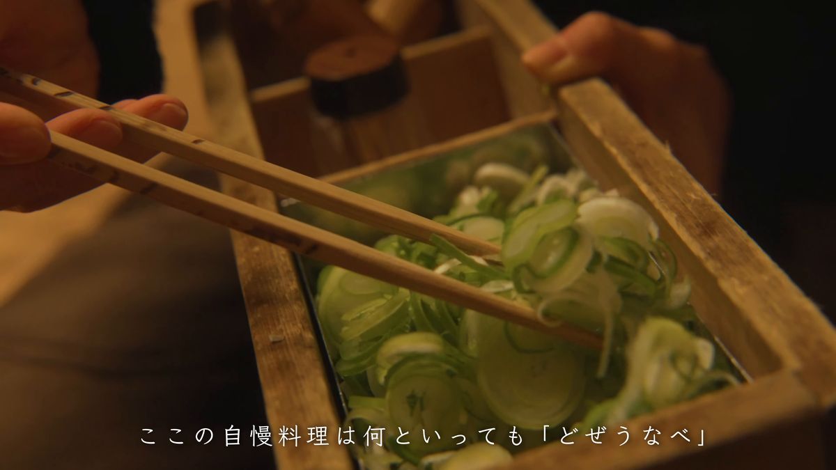 木箱に盛られた刻みネギを箸ですくう