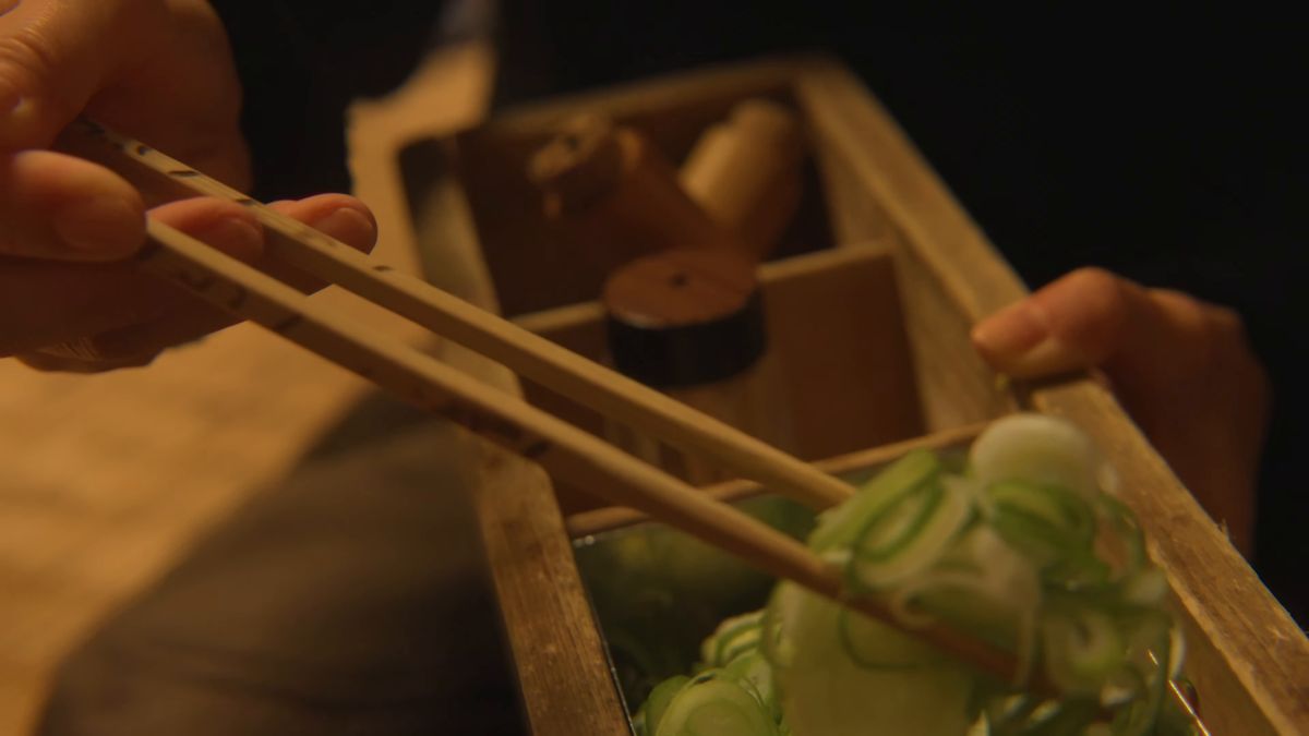 木箱からネギをたっぷりすくう手元