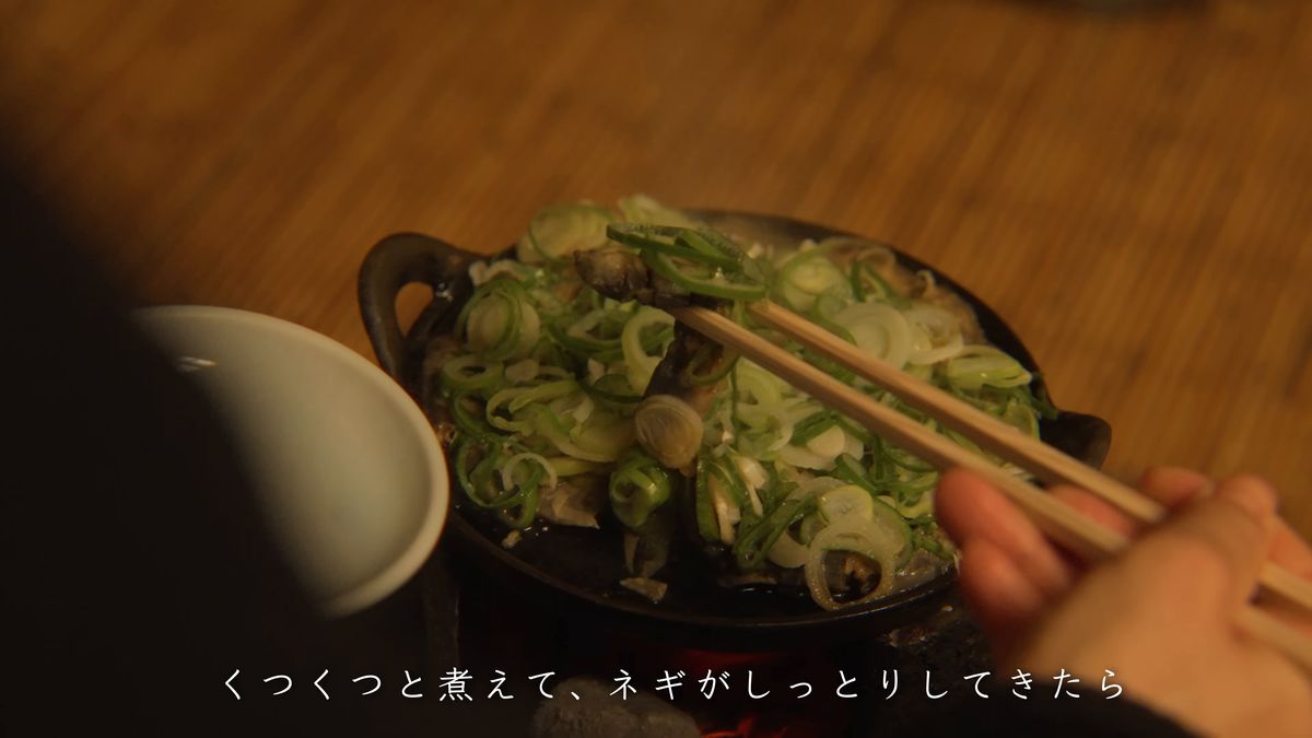 煮えた鍋から箸でどじょうをすくう