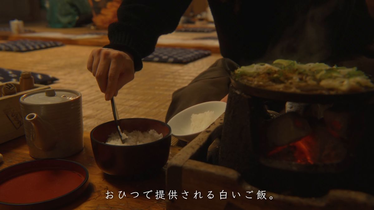 火鉢の脇で、おひつからご飯をよそう