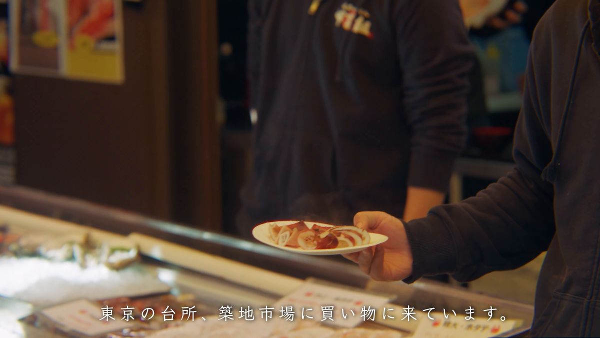 店先で刺身の皿を受け取る人