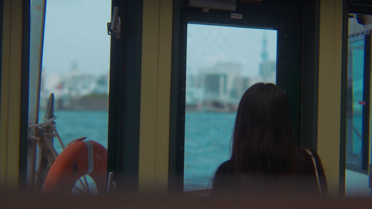 窓辺に座り、川を眺める後ろ姿