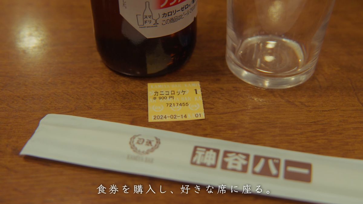 ノンアルコールビールの瓶と「カニコロッケ」の食券