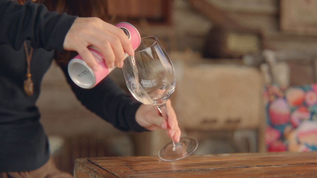 ワイングラスに缶の飲み物を注ぐ手元