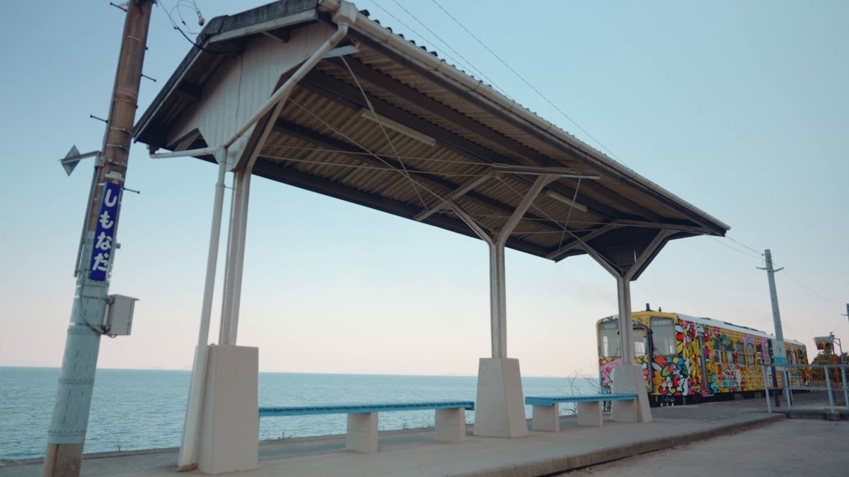 海に面した下灘駅のホームに、花柄の列車が入ってくる