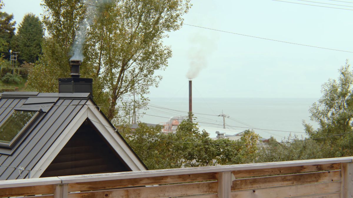 屋根の向こうの海と、煙突から上がる煙