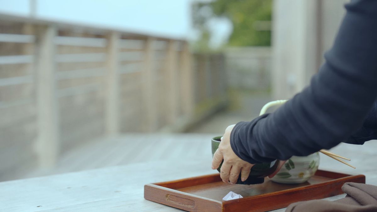 テラスの机で茶碗を手に取る手元