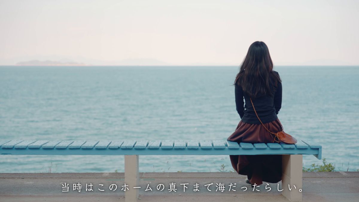 ベンチに座って海を眺める後ろ姿