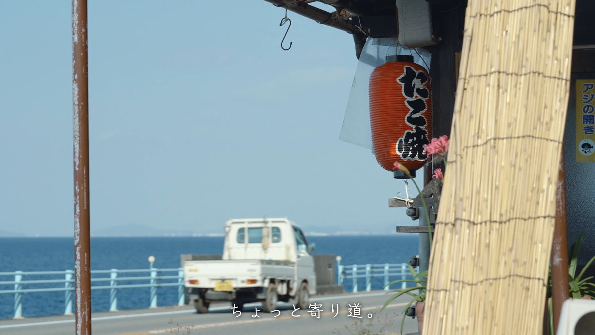 「たこ焼」の赤提灯と、海沿いの道の軽トラック