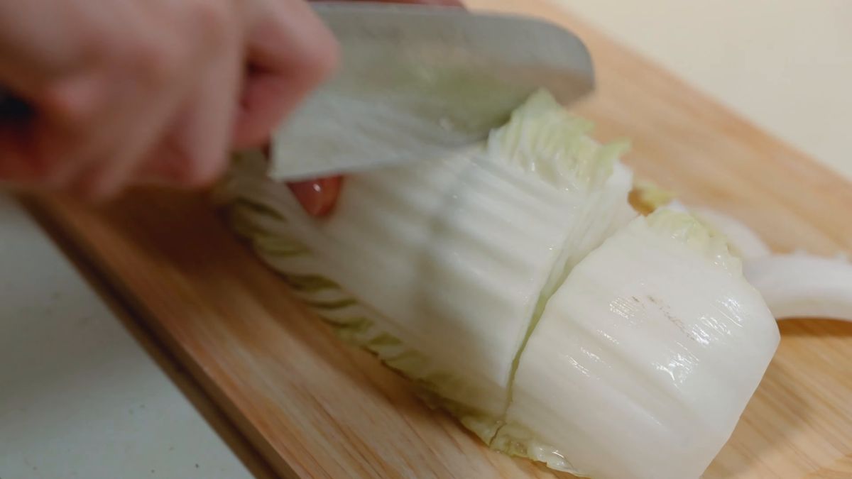 まな板の上で白菜に包丁を入れる