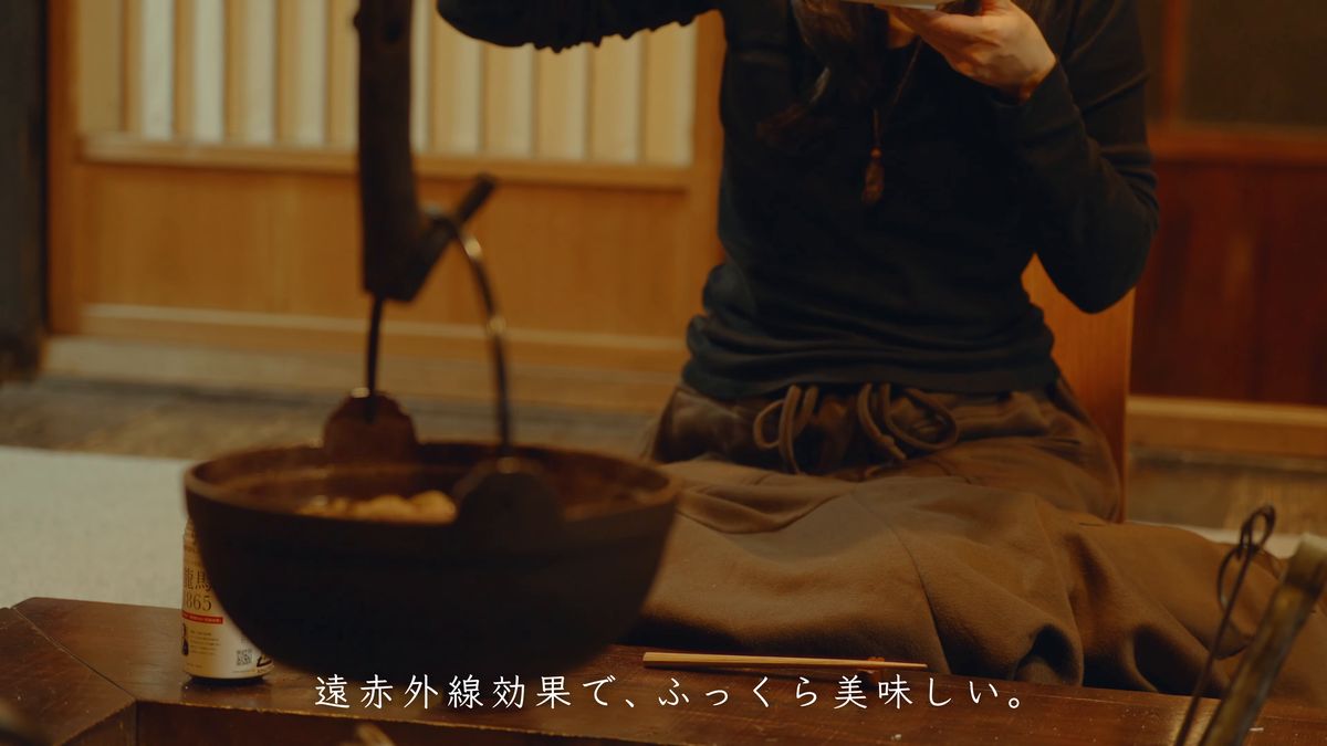 囲炉裏の鍋を前に食事をする