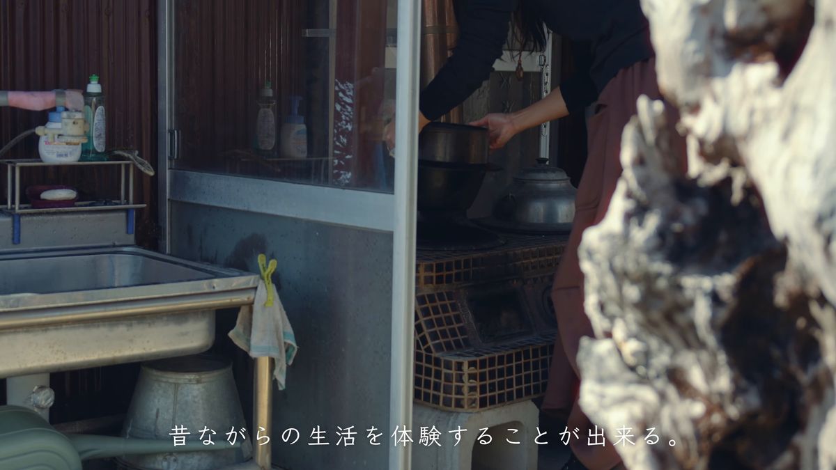 台所の流しの前で釜を抱える後ろ姿