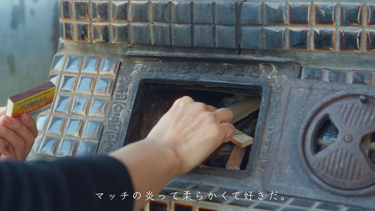 かまどの焚き口でマッチを擦る手元