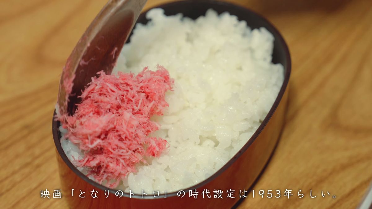 ご飯の上に桃色のでんぶをのせる