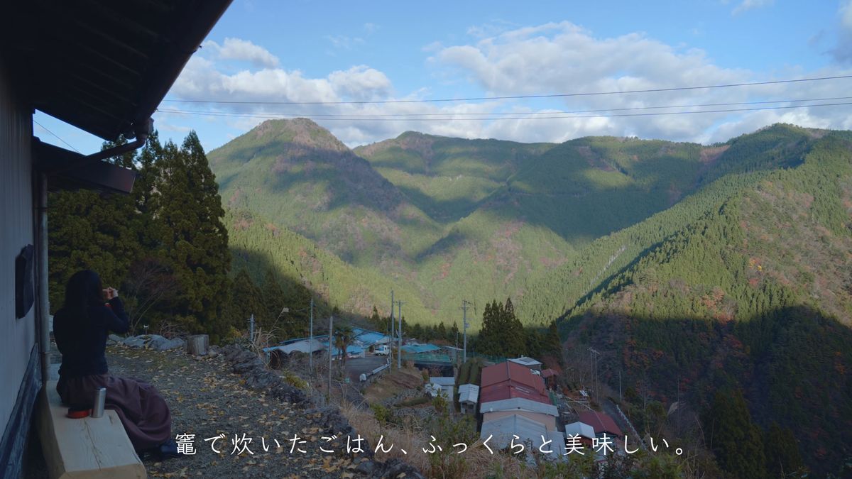 集落を見下ろす縁台に座る後ろ姿