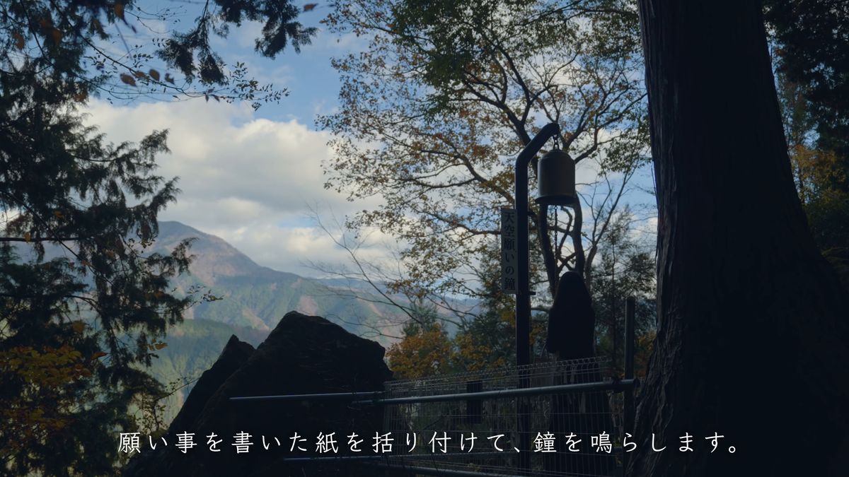 杉の木のそばに下がる鐘と空