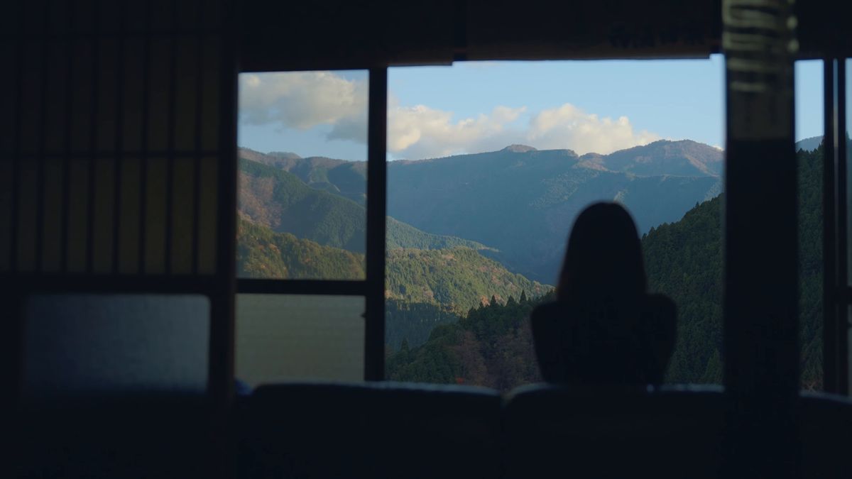 障子越しの山並みと窓辺に座る影
