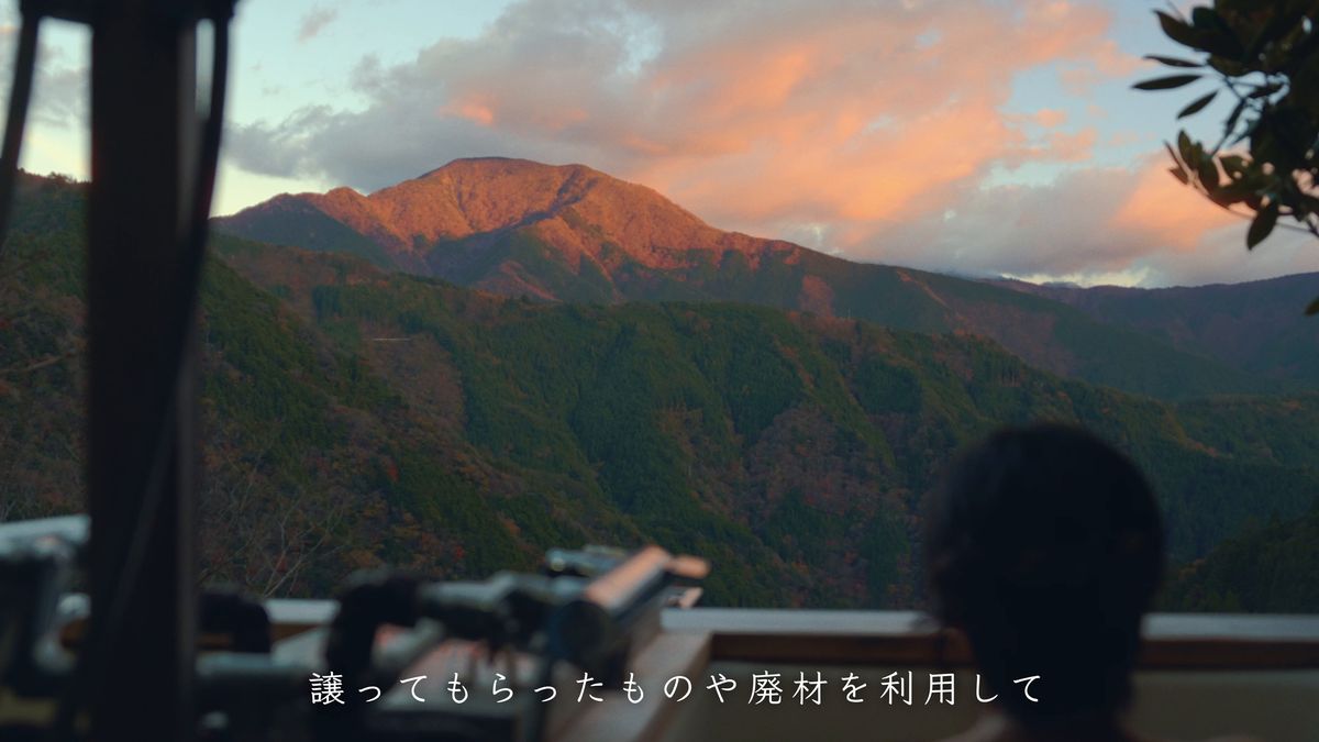 露天風呂から夕焼けの山を眺める後ろ姿