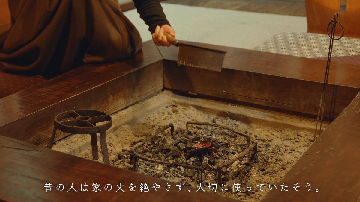囲炉裏の灰の上で熾きる炭と鉄の五徳