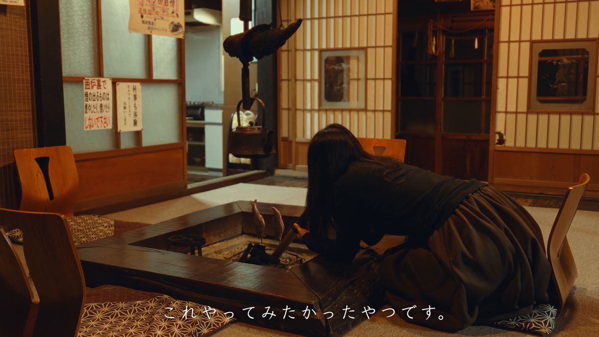 囲炉裏の前にかがんで火を吹く後ろ姿