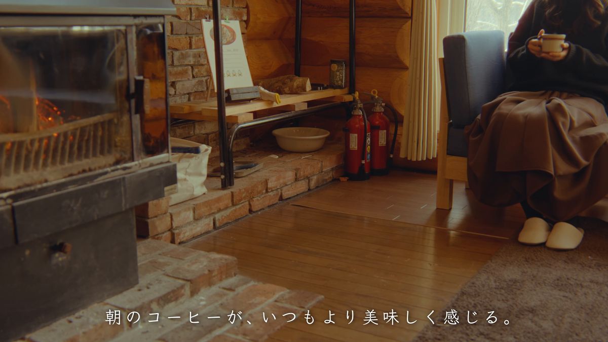 暖炉のそばの椅子でコーヒーを飲む後ろ姿