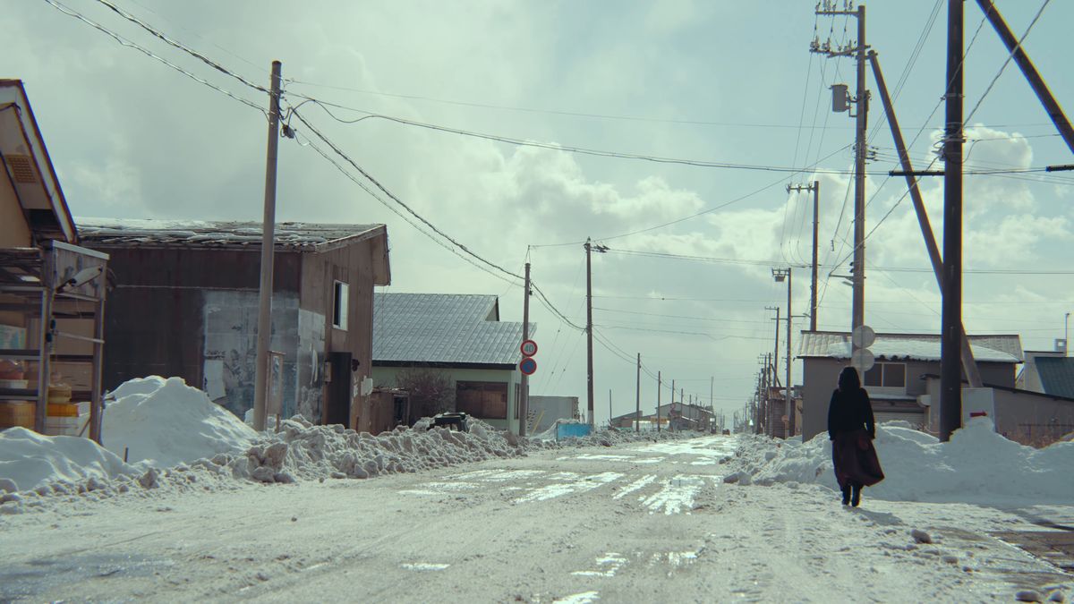 雪の積もった町の通りを歩く後ろ姿