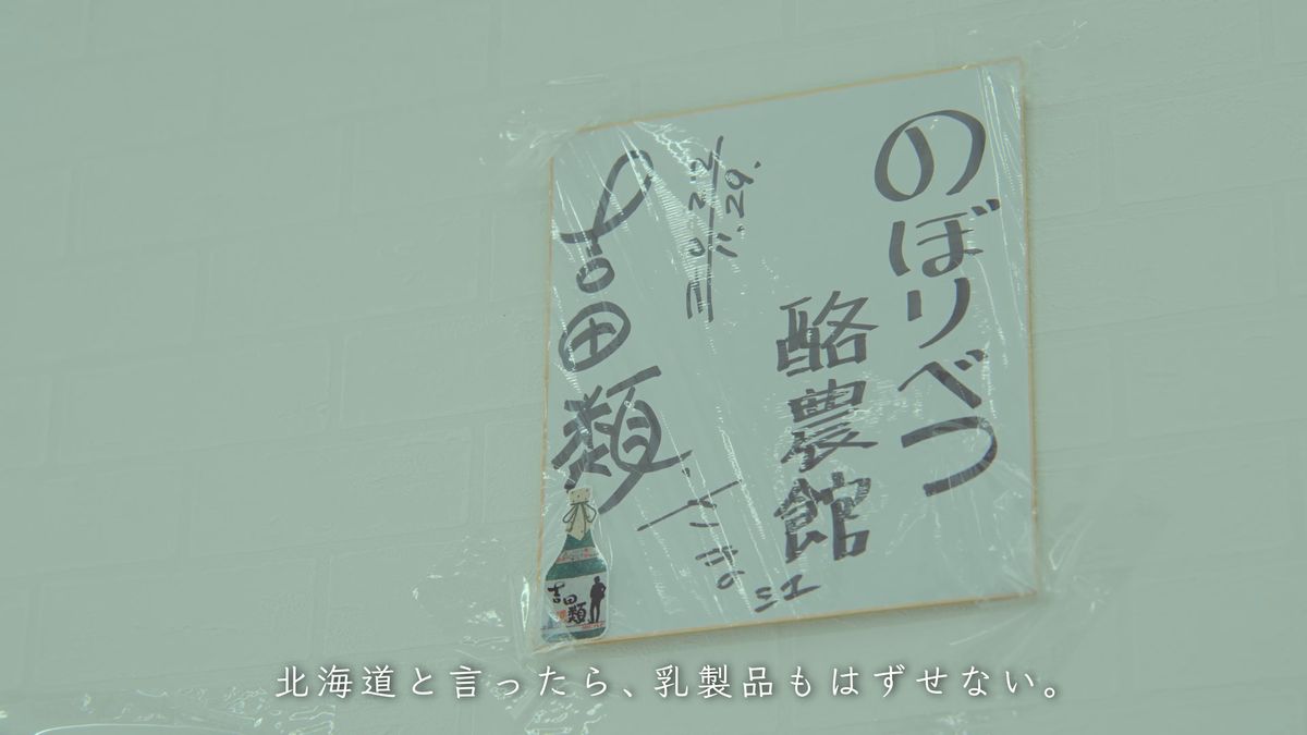 白い壁に貼られた、酪農館の名が書かれた色紙