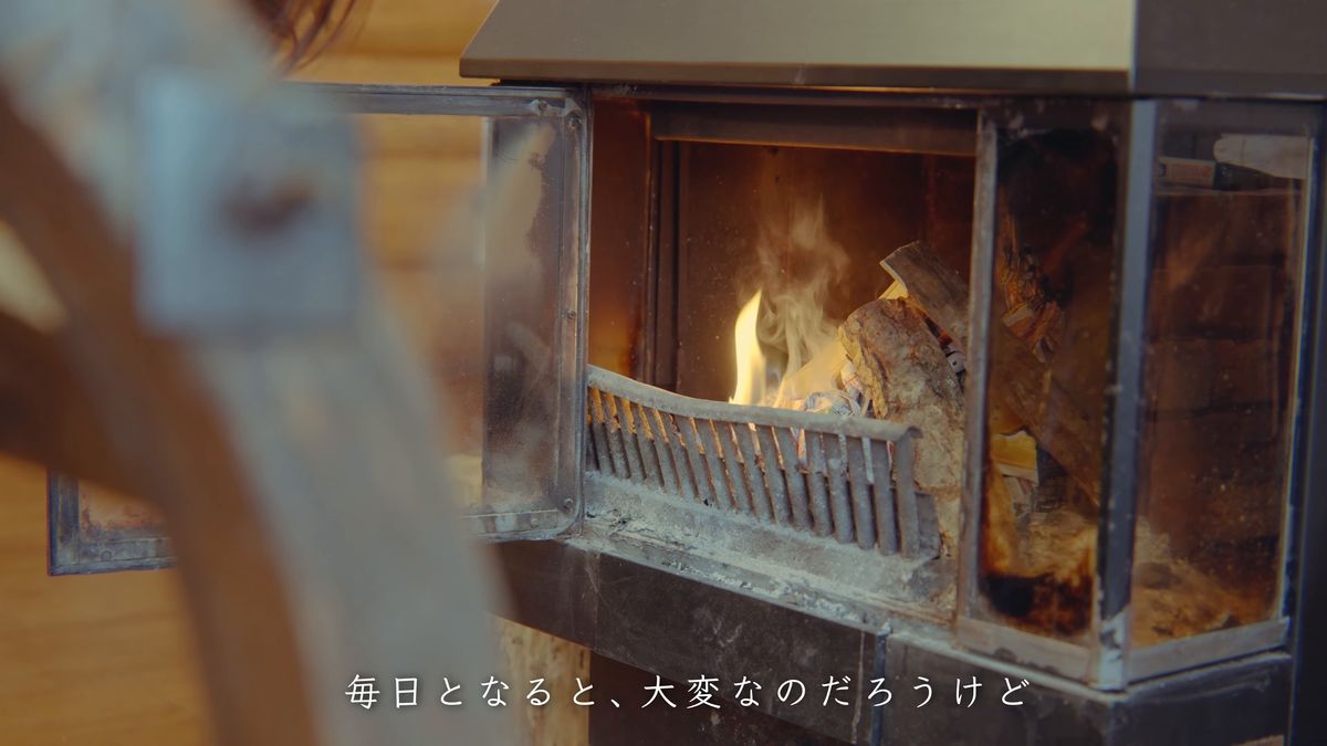 火ばさみで暖炉に薪を入れる手元