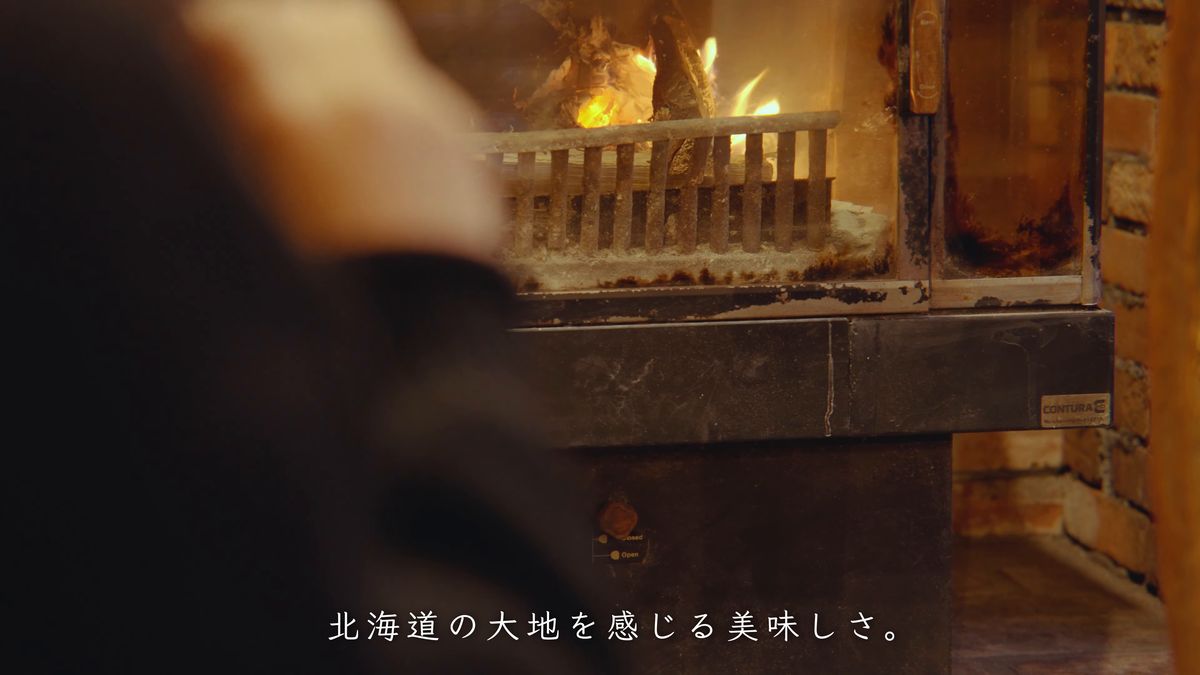 炎の前で薪を足す手元