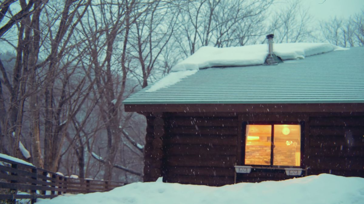 屋根に雪を積もらせた煙突のある小屋