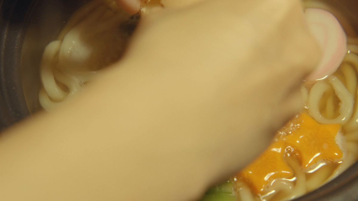 土鍋にうどんと具を入れる手元