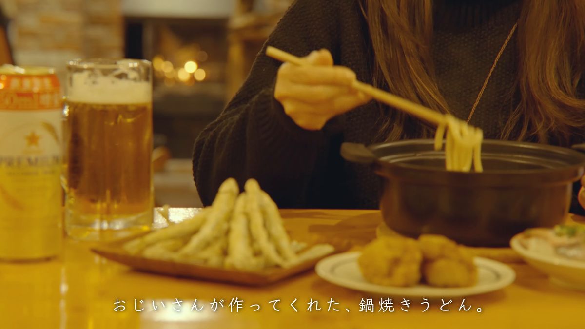 グラスと唐揚げを前にうどんをすする手元