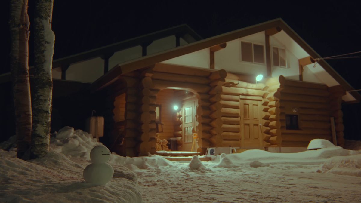 夜の雪に灯りのともったログハウスと雪だるま