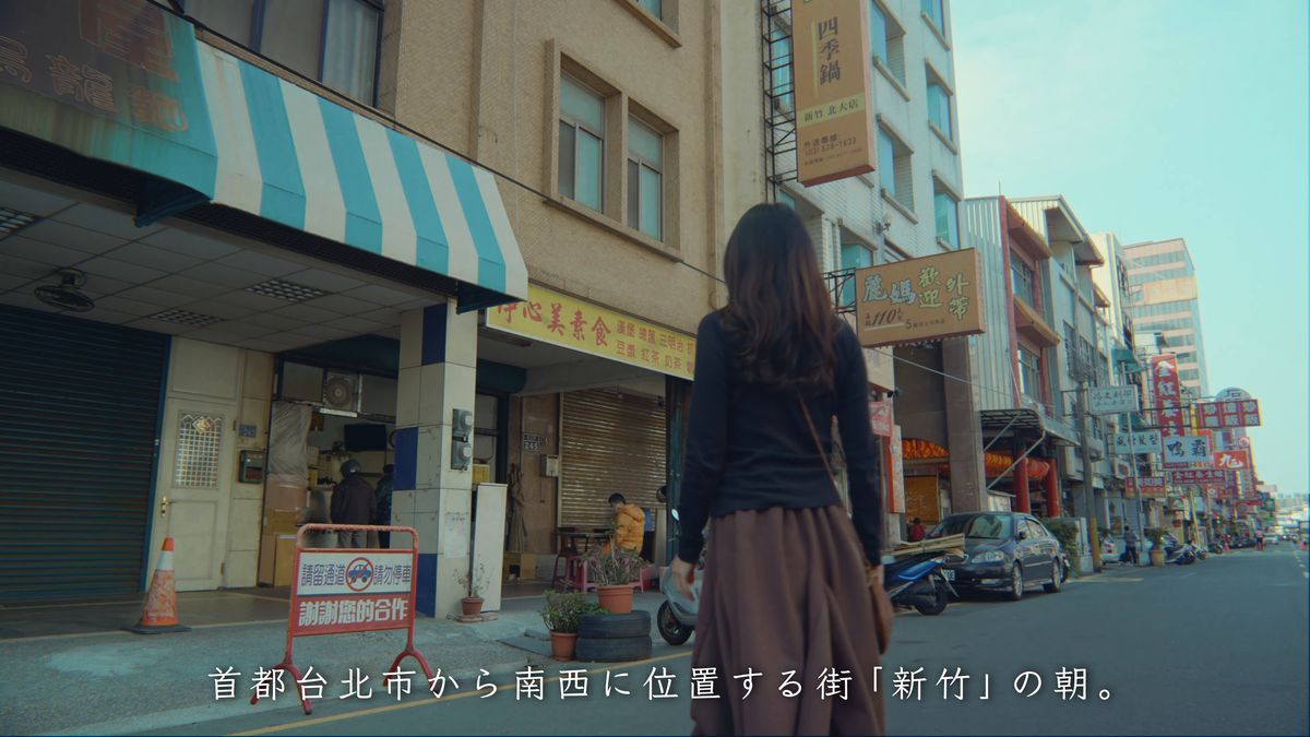 青いひさしの店の前を歩く後ろ姿
